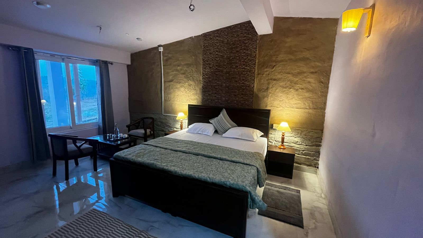 Rustic bedroom suite with a stone feature wall at Oorja Eco Retreat
